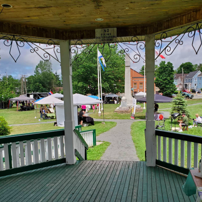 Looking out from a gazebo onto a field willed with vendors' tents